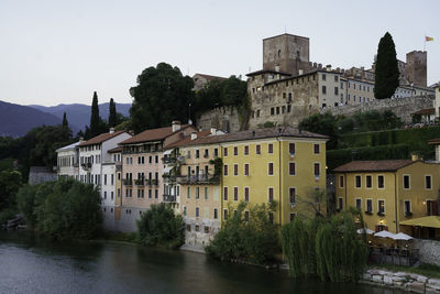 Buildings by river against clear sky