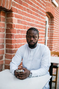 Portrait of senior man sitting against wall