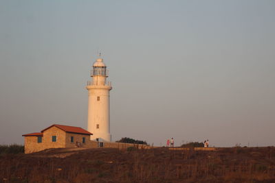 Lighthouse amidst buildings against sky