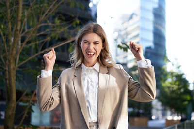 Portrait of young woman standing against building