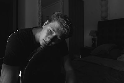 Young man sitting on bed at home