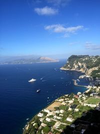 High angle view of city by sea against blue sky