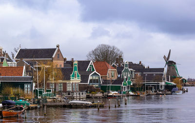 Buildings by river against sky