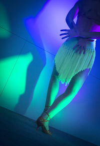 Low section of woman dancing in illuminated nightclub