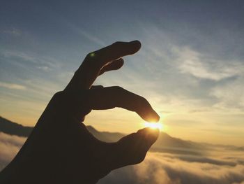 Close-up of silhouette hand against sky during sunset