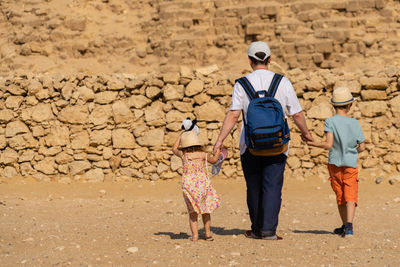 Father and children walk in front of the chephren pyramid on the giza plateau