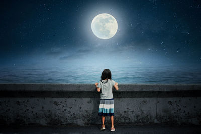 Full length rear view of girl standing against moon