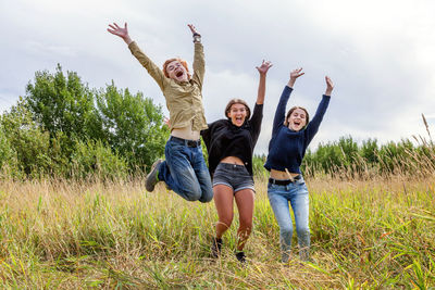 Group of three friends boy and two girls running and having fun together outdoors