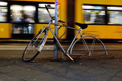 Abandoned bicycle leaning on pole in front of tramway