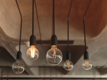 Low angle view of illuminated light bulbs hanging from ceiling