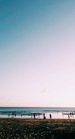 Group of people on beach against clear sky