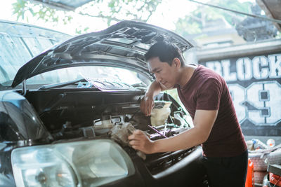 Side view of young man holding car