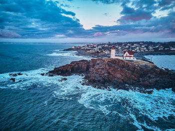 Lighthouse in sea against sky at dusk