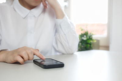 Midsection of woman using mobile phone on table