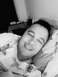 Portrait of smiling man lying on bed at home