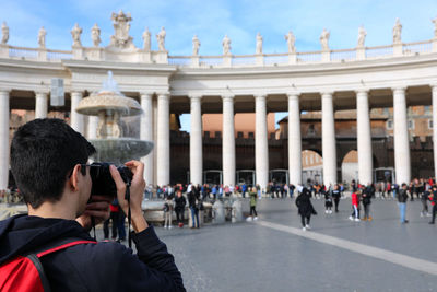 Rear view of teenage boy photographing in city