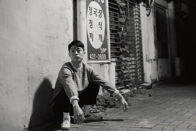 Man crouching on footpath in city