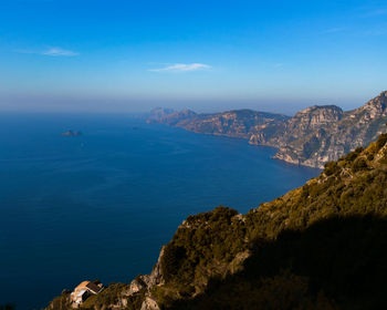 Scenic view of sea and mountains against blue sky