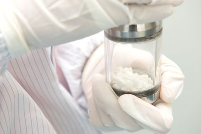 Close-up of doctor wearing gloves holding pills bottle