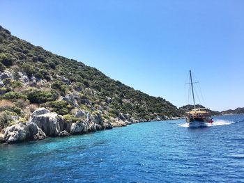 Sailboat sailing on sea against clear blue sky