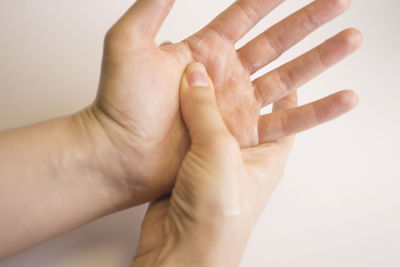Cropped image of woman applying cream on hand against white background