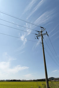 Low angle view of electricity pylon on field against sky