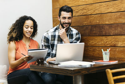 Young woman using laptop while sitting on table