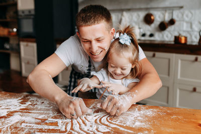 Funny happy dad and daughter baby cook together fool around and play with flour in  kitchen at home