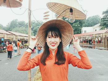 Happy woman wearing asian style conical hat at street market