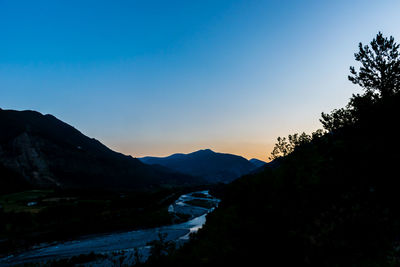 Scenic view of silhouette mountains against clear sky at sunset