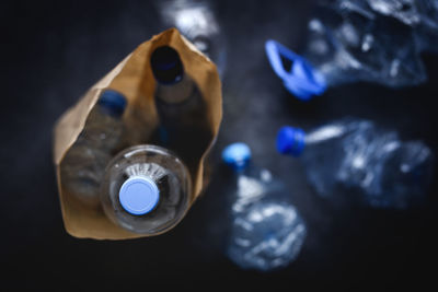 From above dirty paper sack with discarded plastic bottles placed on black background