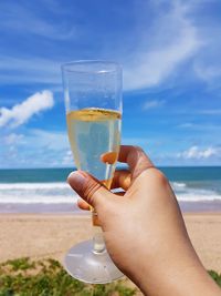 Midsection of man drinking glass on beach