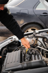 Close up view of the senior man inspecting car oil level 