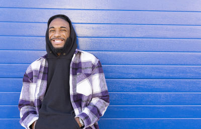 Portrait of smiling young woman standing against wall