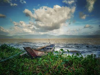 Abandoned boat moored on beach against sky