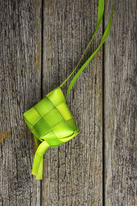 Close-up of green leaf on wooden table against wall