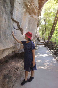 A woman walking in the forest and a large cliff