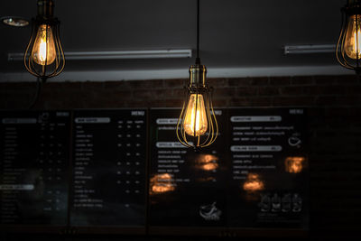 Close-up of illuminated light bulb hanging on ceiling