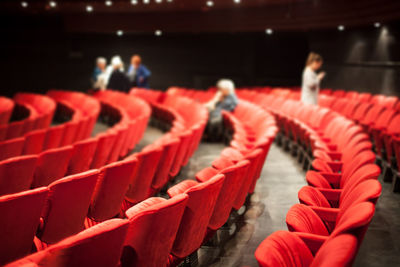 Defocused people and red chairs in auditorium