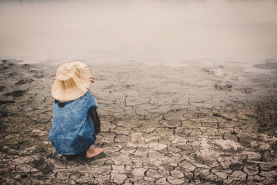 Rear view of girl crouching by pond