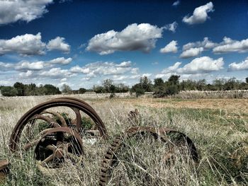 Abandoned car on field against sky