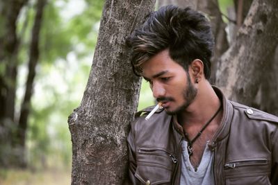 Young man in tree trunk in forest