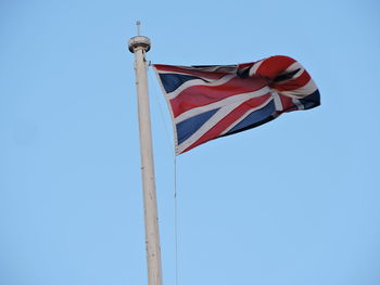 Low angle view of flag against clear blue sky