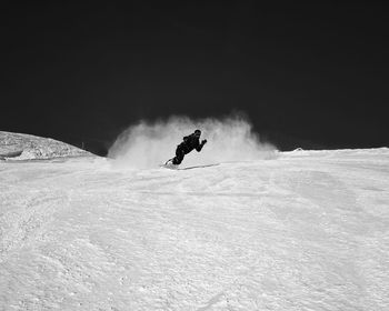 Man snowboarding on snowy land against clear sky
