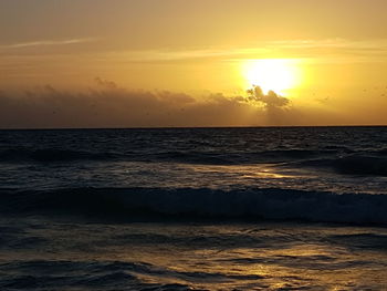 Scenic view of sea against dramatic sky during sunset