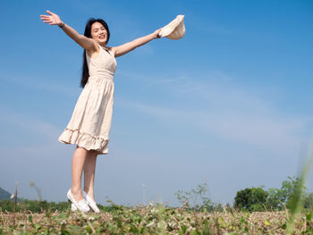 Woman with arms raised standing on land against sky
