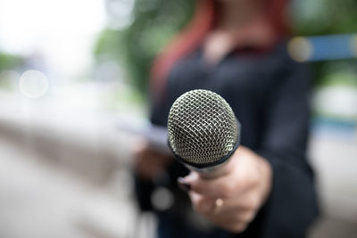 Midsection of man holding microphone