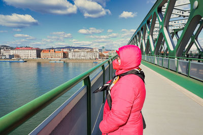 Rear view of woman on bridge against sky in city