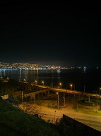 Illuminated bridge over city against sky at night