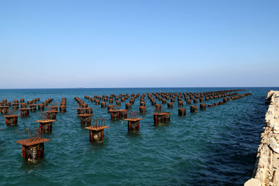 Wooden posts in sea against clear sky